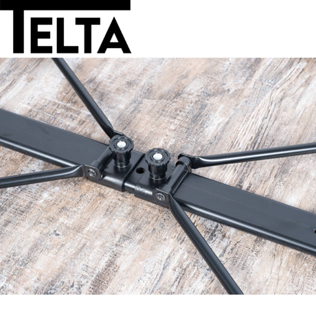 Telta Bornholm medium camping table with a sturdy design, set up outdoors on grass with a scenic backdrop.