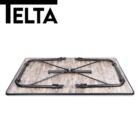 Telta Bornholm medium camping table set up outdoors with a picnic scene and a scenic background.